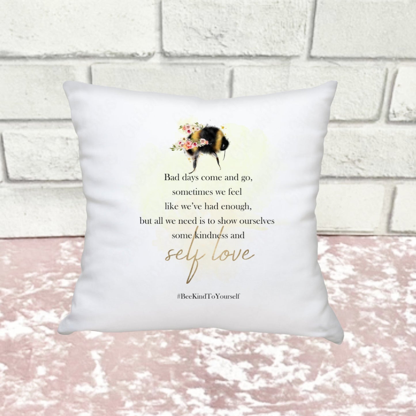 a mini white cushion featuring a bee and text against a pink and white background.