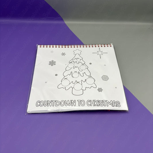 Colouring book with a Christmas tree design and 'Countdown to Christmas' text on a purple surface.