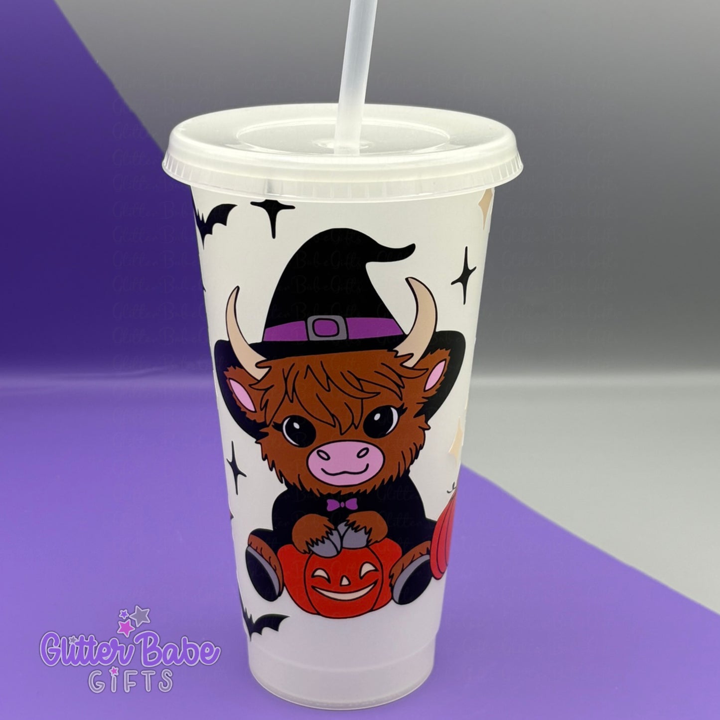 Clear tumbler with a cow wearing a witch hat and pumpkin design on a purple and gray background.