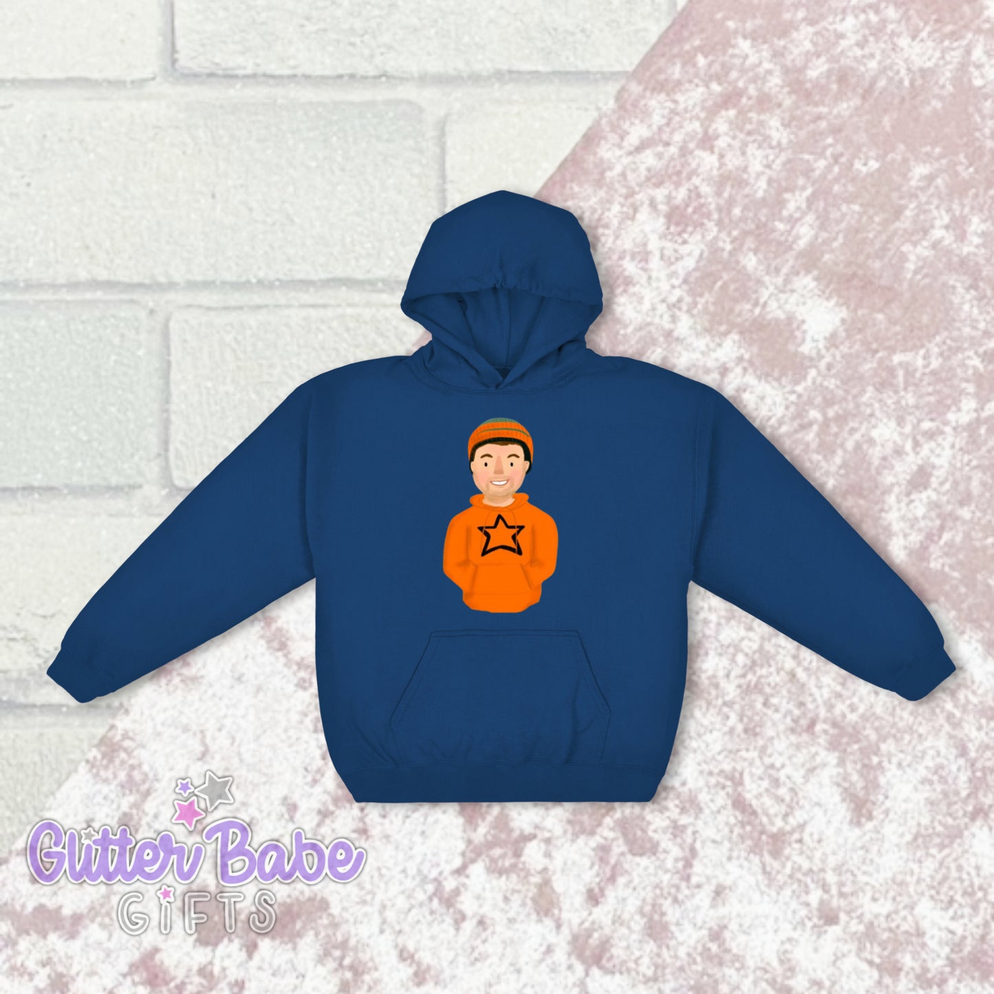 A blue hoodie with a graphic of a cartoon character on the front centre, positioned above a pocket. The hoodie is displayed against a brick wall backdrop.