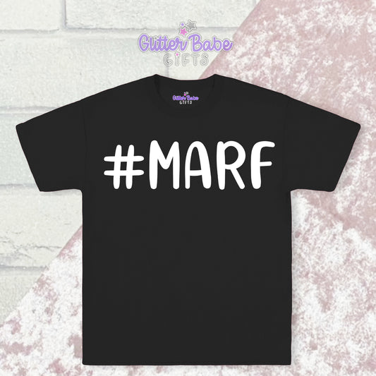 Black T-shirt with white writing saying #marf with a pink and white backdrop
