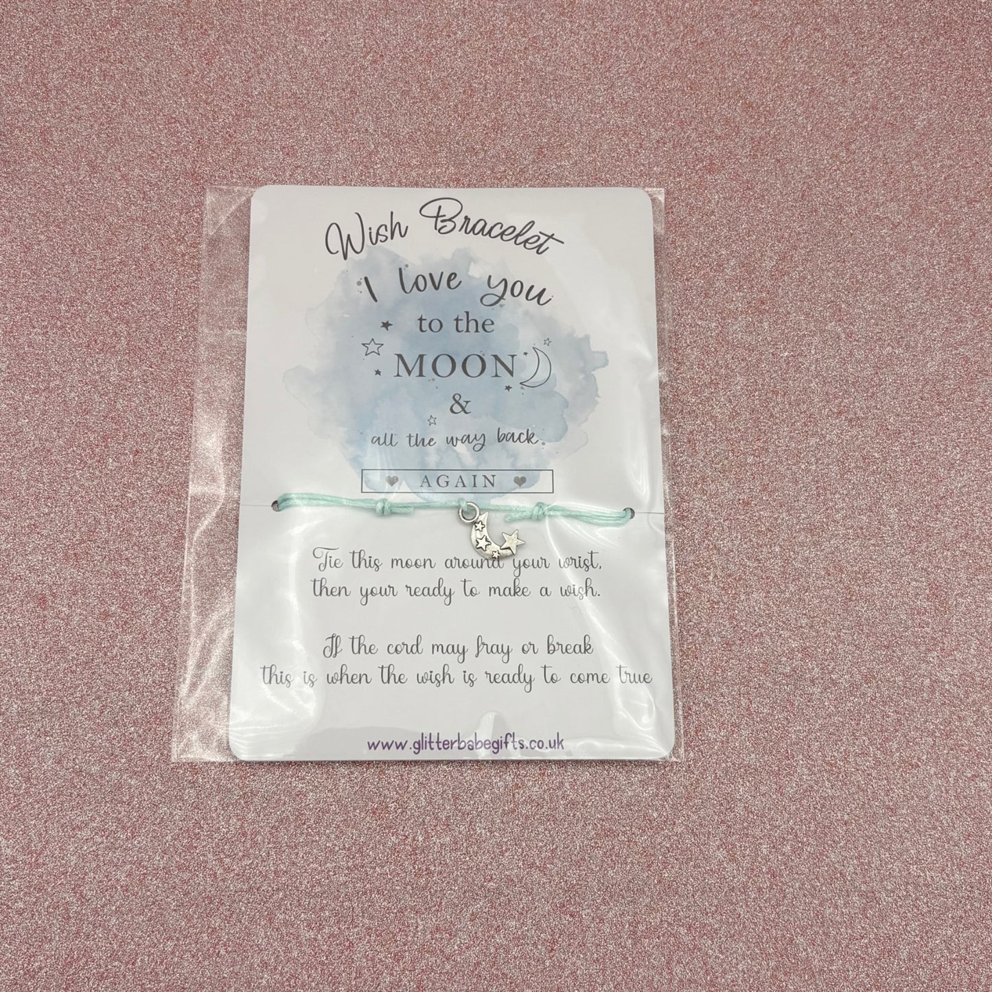 Wish bracelet in packaging with text on a pink background