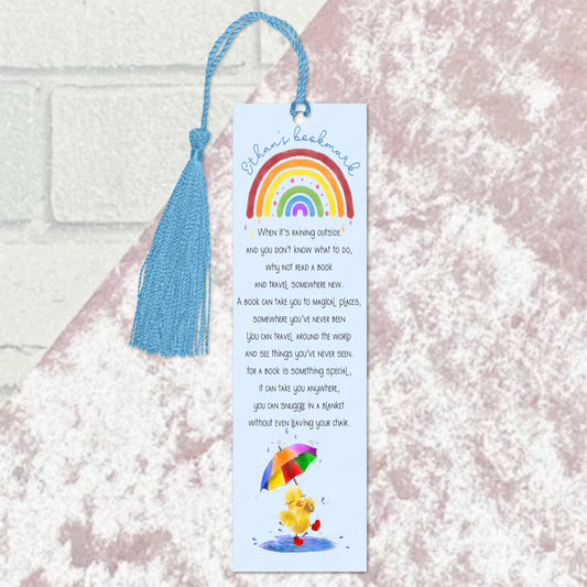 blue duck with a rainbow bookmark with tassel against a light pink velvet background