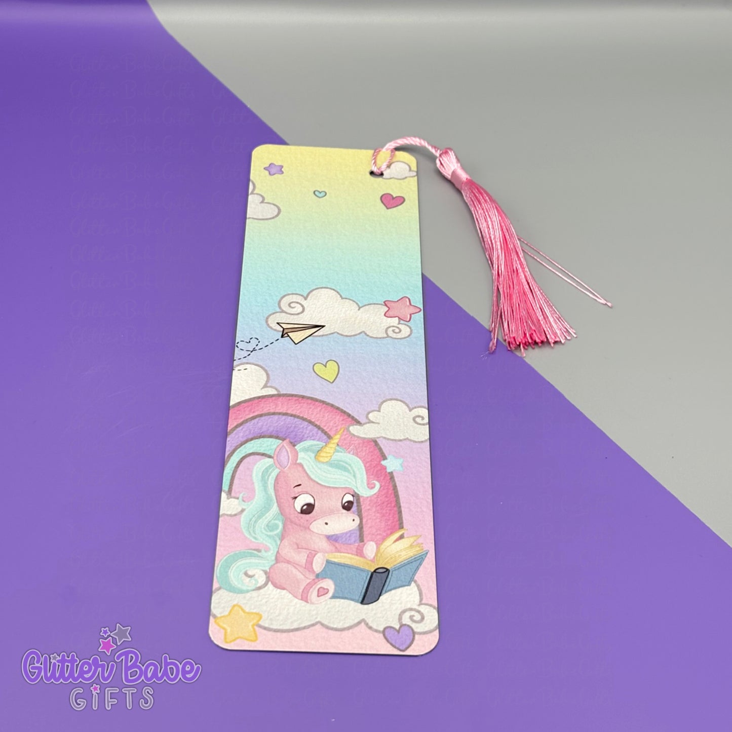 Colorful bookmark with a cartoon unicorn reading a book on a purple and gray background, featuring the brand 'Glitter Babe Gifts'.