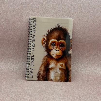 Notebook with a monkey illustration and text on a light pink background