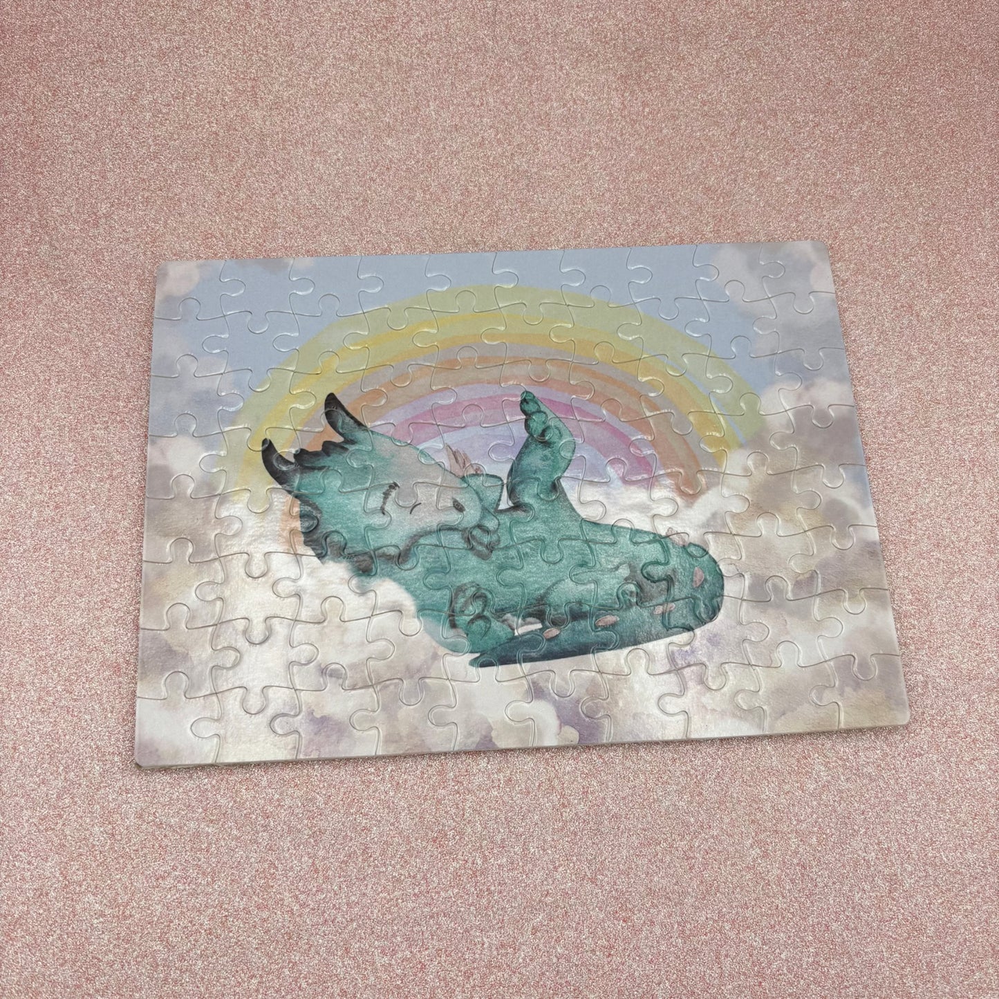 Jigsaw puzzle with a dragon and rainbow design on a pink surface