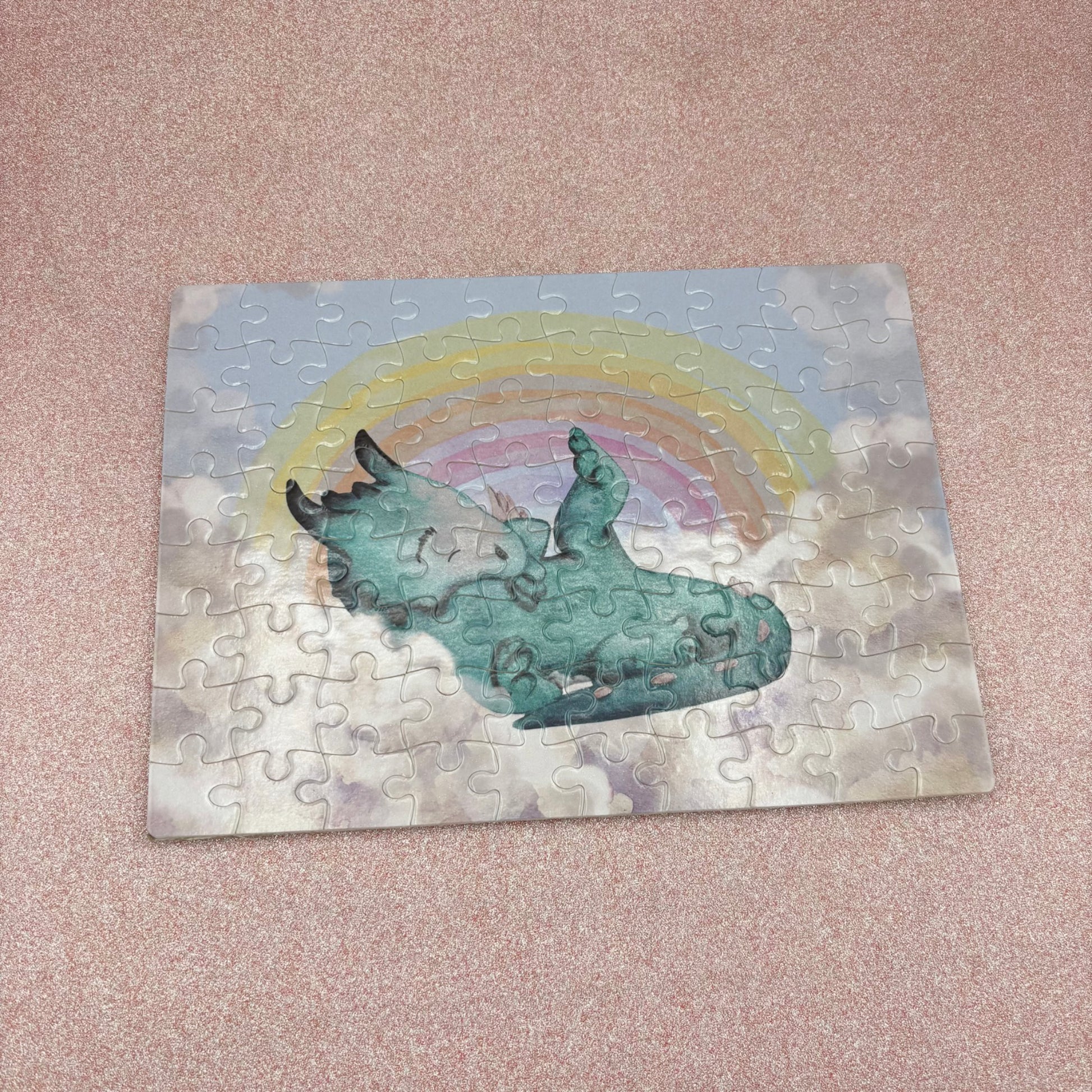 Jigsaw puzzle with a dragon and rainbow design on a pink surface