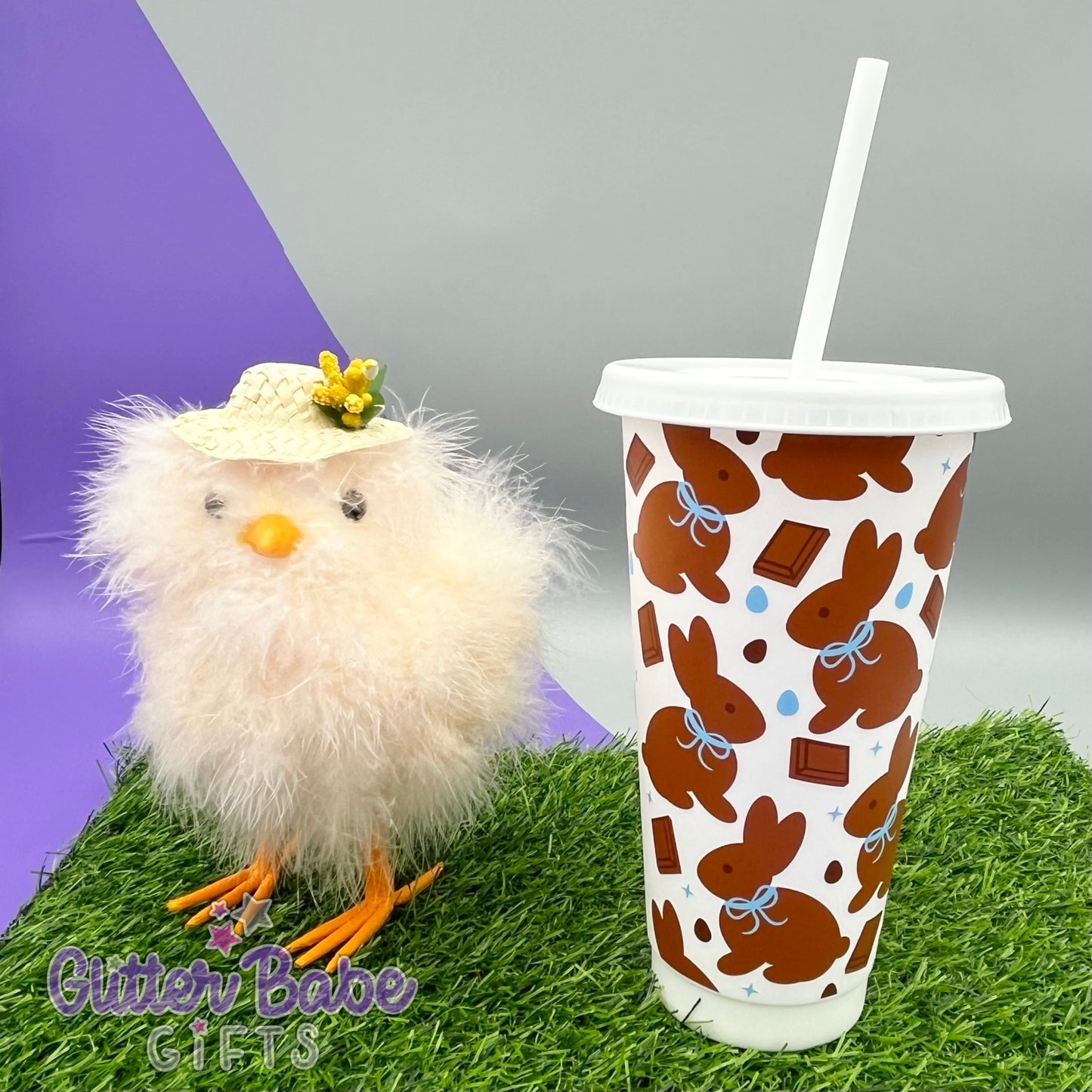 white cold cup with chocolate coloured bunnies with blue ribbon with easter chick and grass as a background