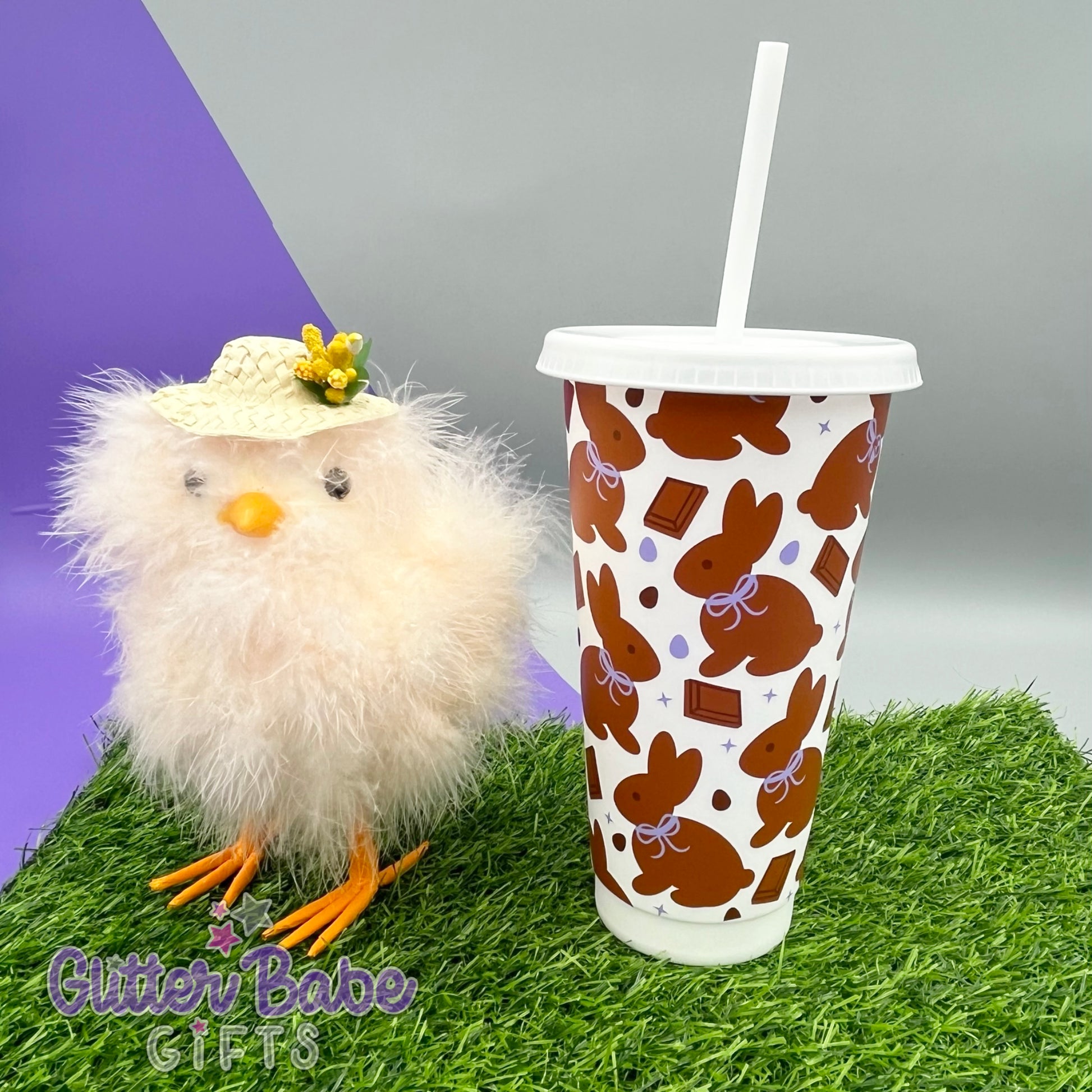 easter chick next to white tumbler that has chocolate coloured bunnies and egg pattern with lilac on some eggs and the ribbon