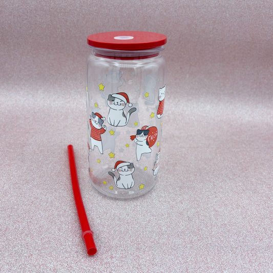 Clear tumbler with red lid and straw, featuring cartoon cats in Santa hats on a light Pink background