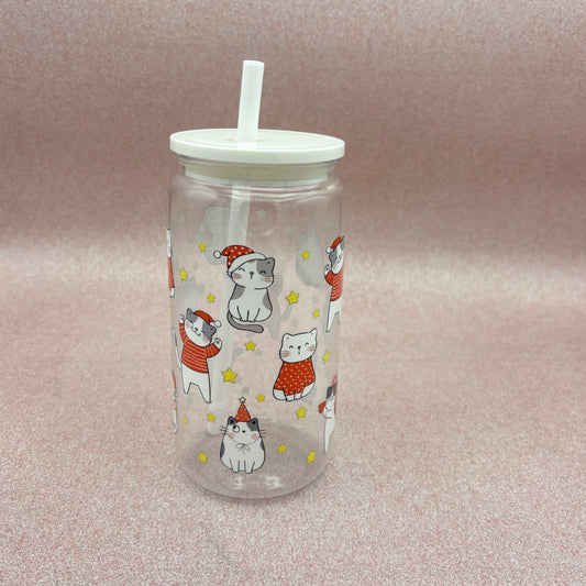 Clear tumbler with white lid and straw, featuring cartoon cats in Santa hats on a light Pink background