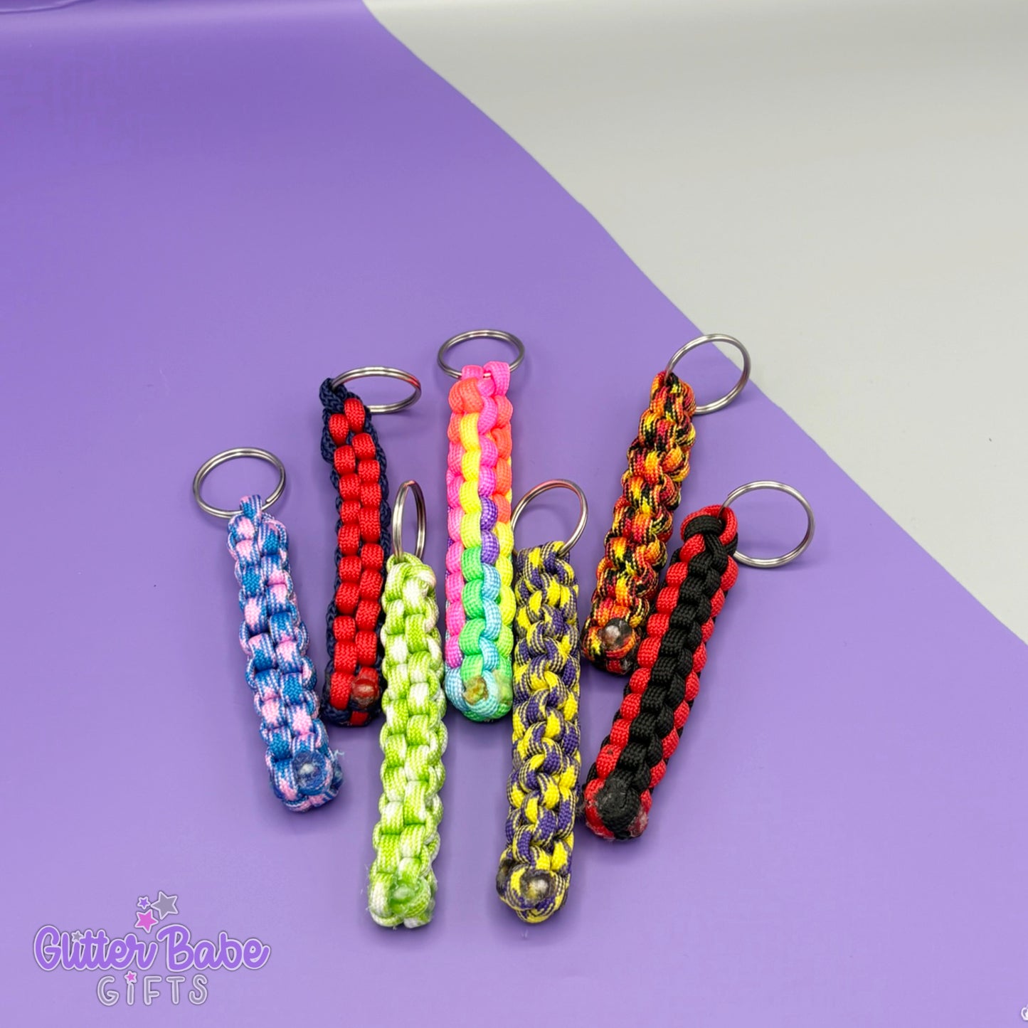 A selection of colourful paracord fob keyrings against a purple and grey backdrop.