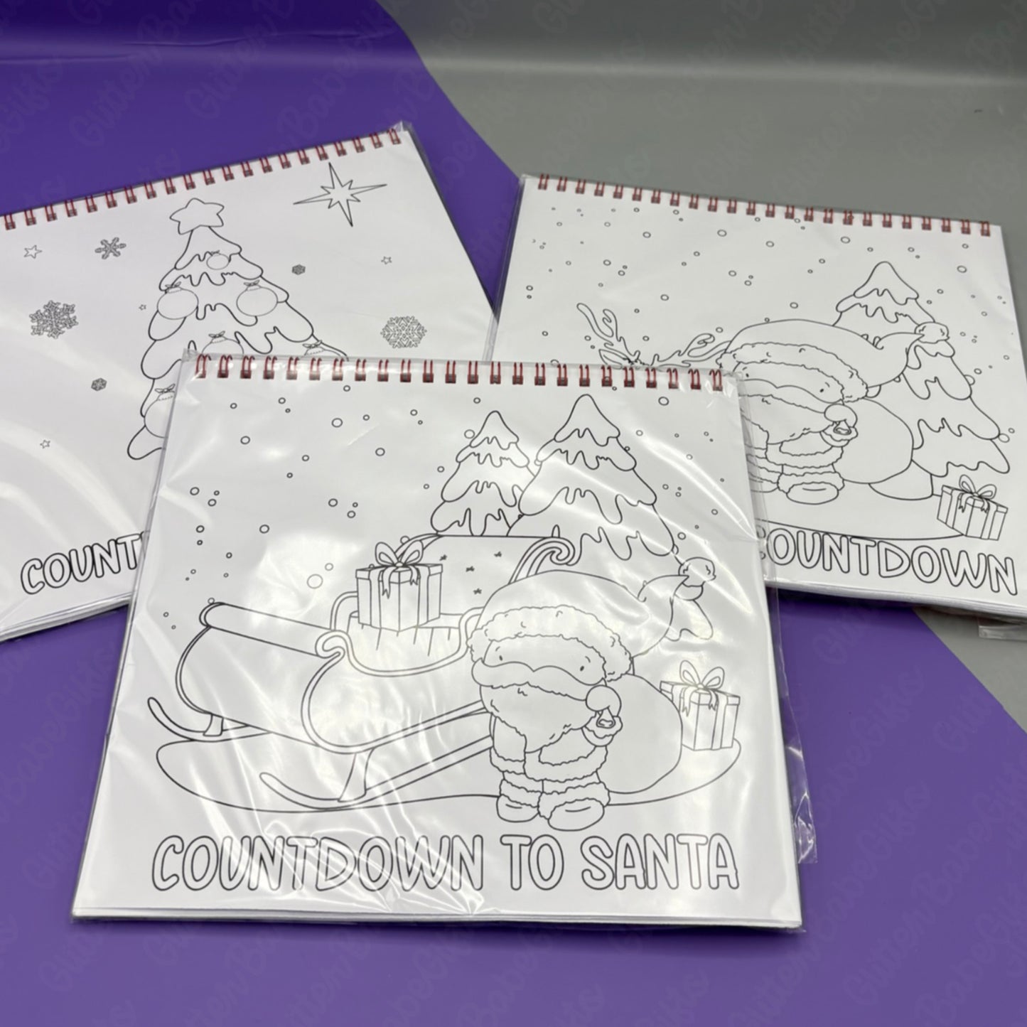 Colouring books with Christmas-themed illustrations on a purple surface