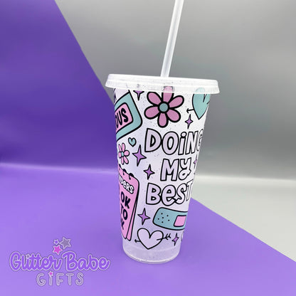A frosted glitter cold cup with doing my best quote and hearts flowers and plaster design, Cup is on a  purple and grey background. 