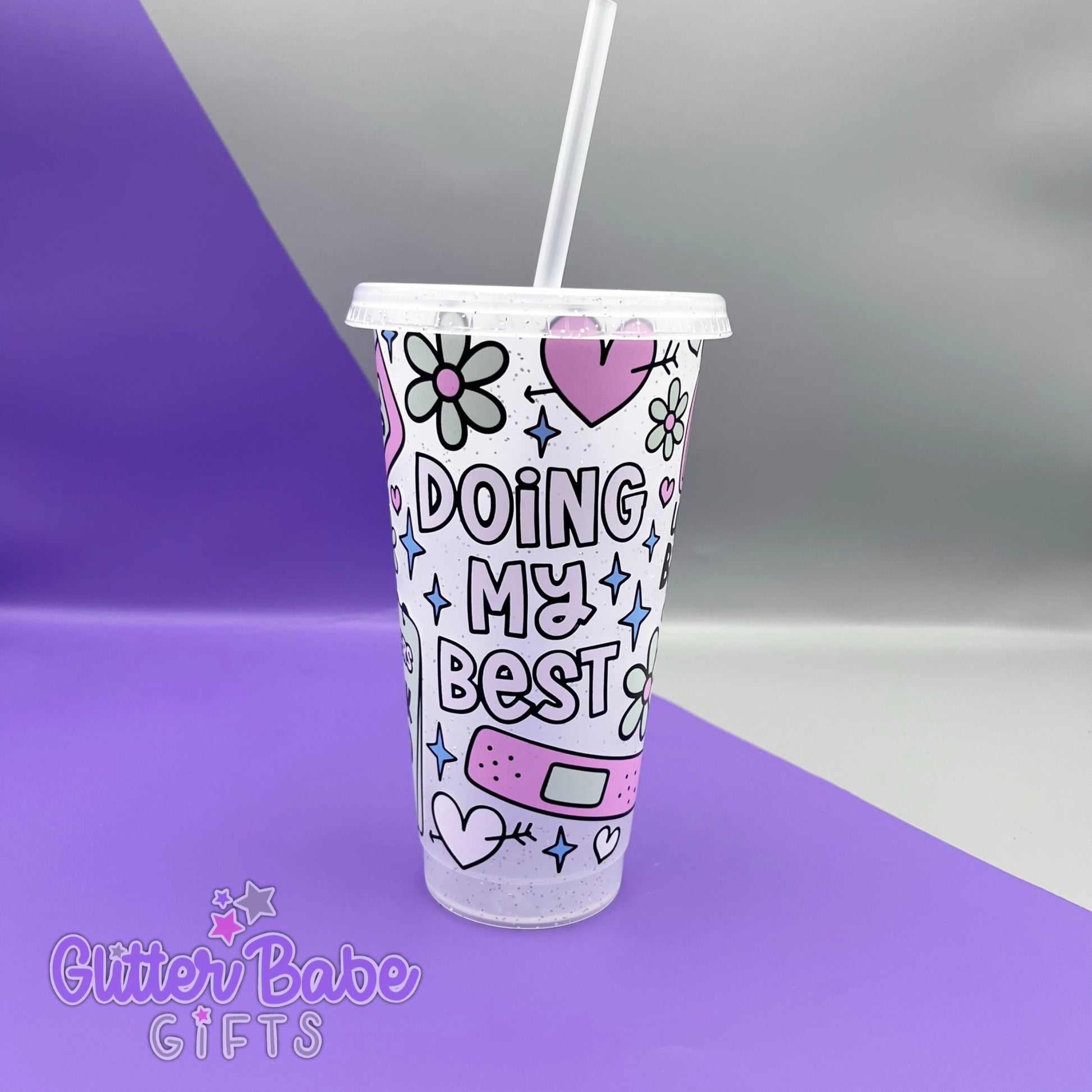 A frosted glitter cold cup with doing my best quote and hearts and plaster design, Cup is on a  purple and grey background. 