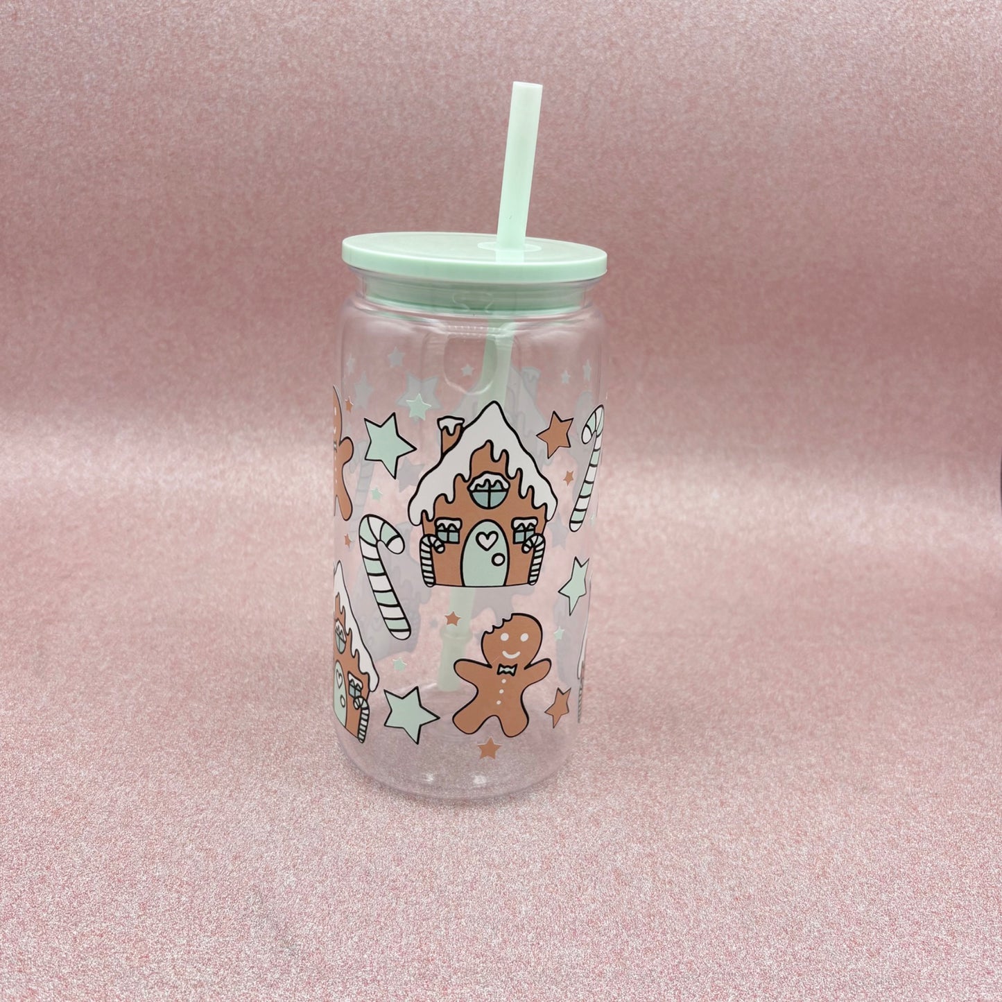Clear tumbler with Christmas-themed designs on a pink background