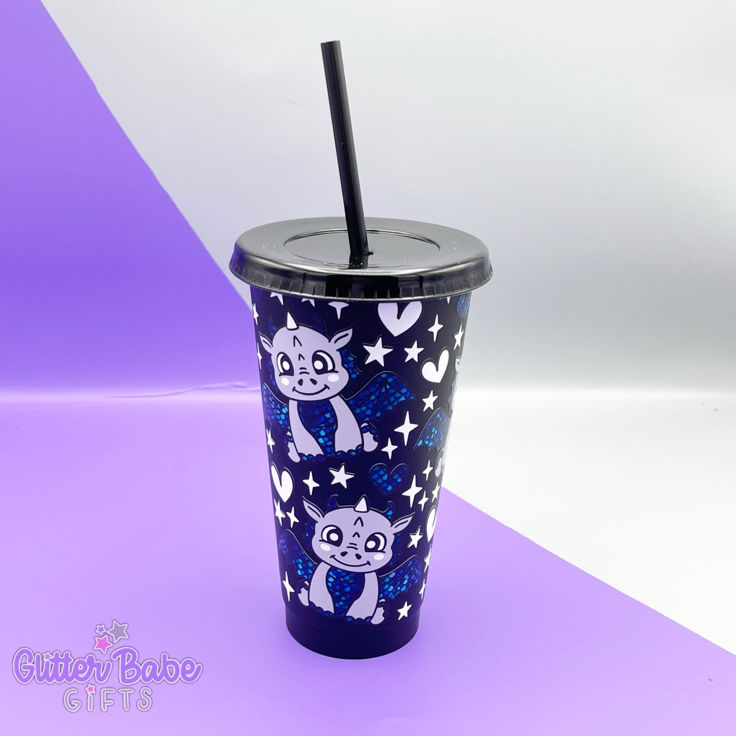 A black tumbler with grey and blue scaled dragon , white hearts and stars design on a purple and grey backdrop