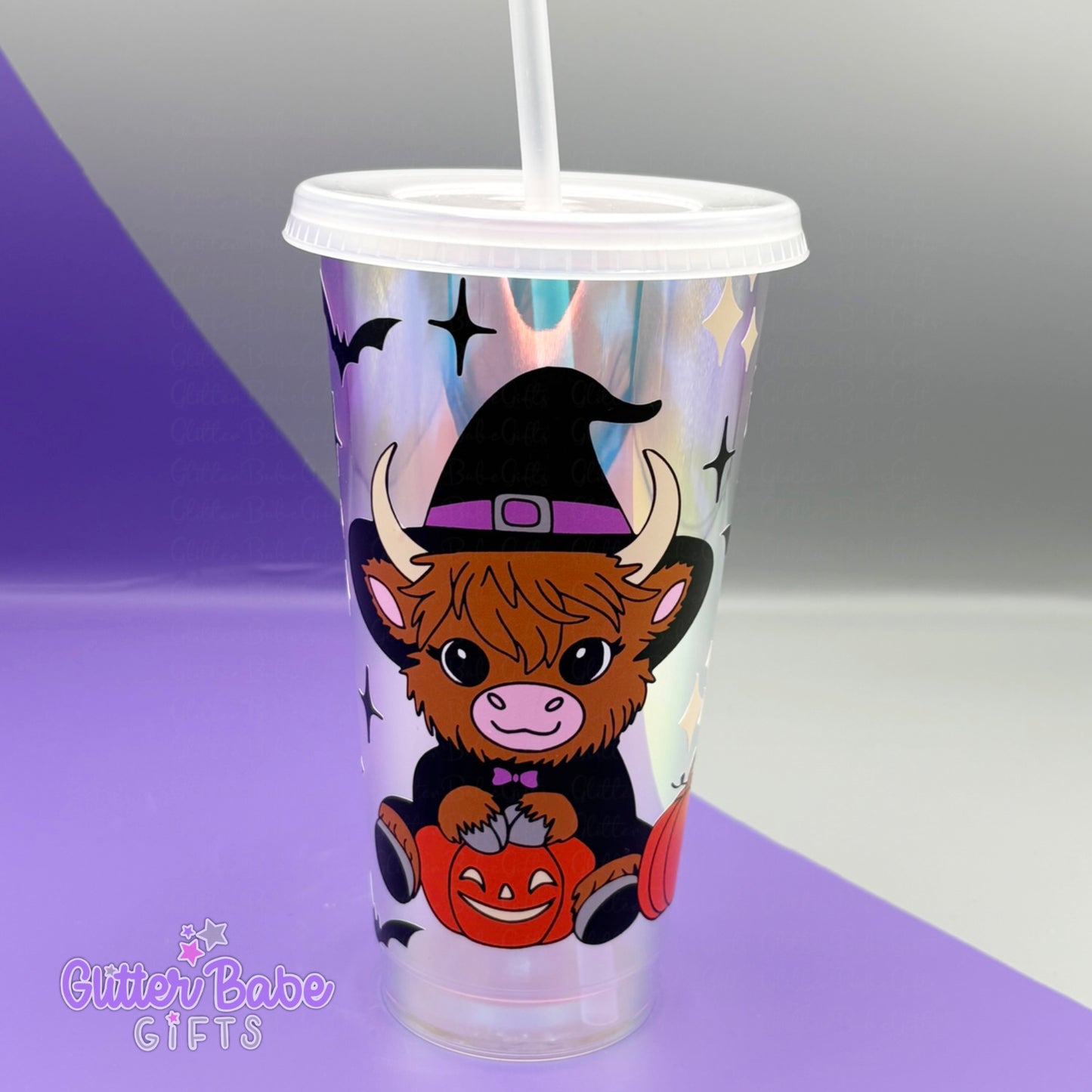 Tumbler with a cow wearing a witch hat and pumpkin design on a gradient background.