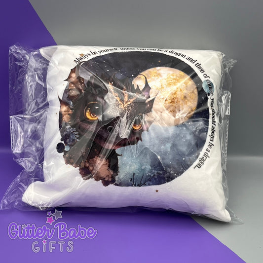 A cushion in cellophane bag with a black and gold dragon design on it. cushion is against a purple and grey background.
