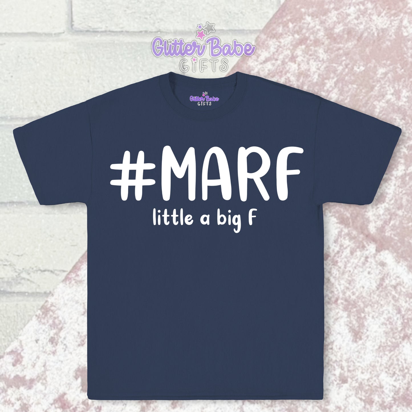 Navy coloured T-shirt with white writing saying #marf little a big f with a pale pink and white backdrop