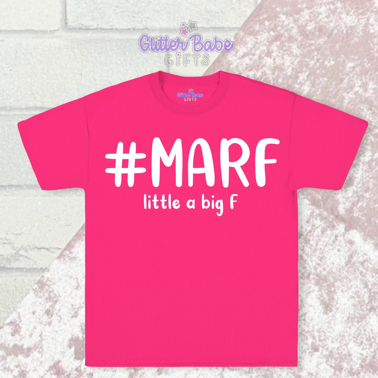 Pink T-shirt with white writing saying #marf little a big f with a pale pink and white backdrop