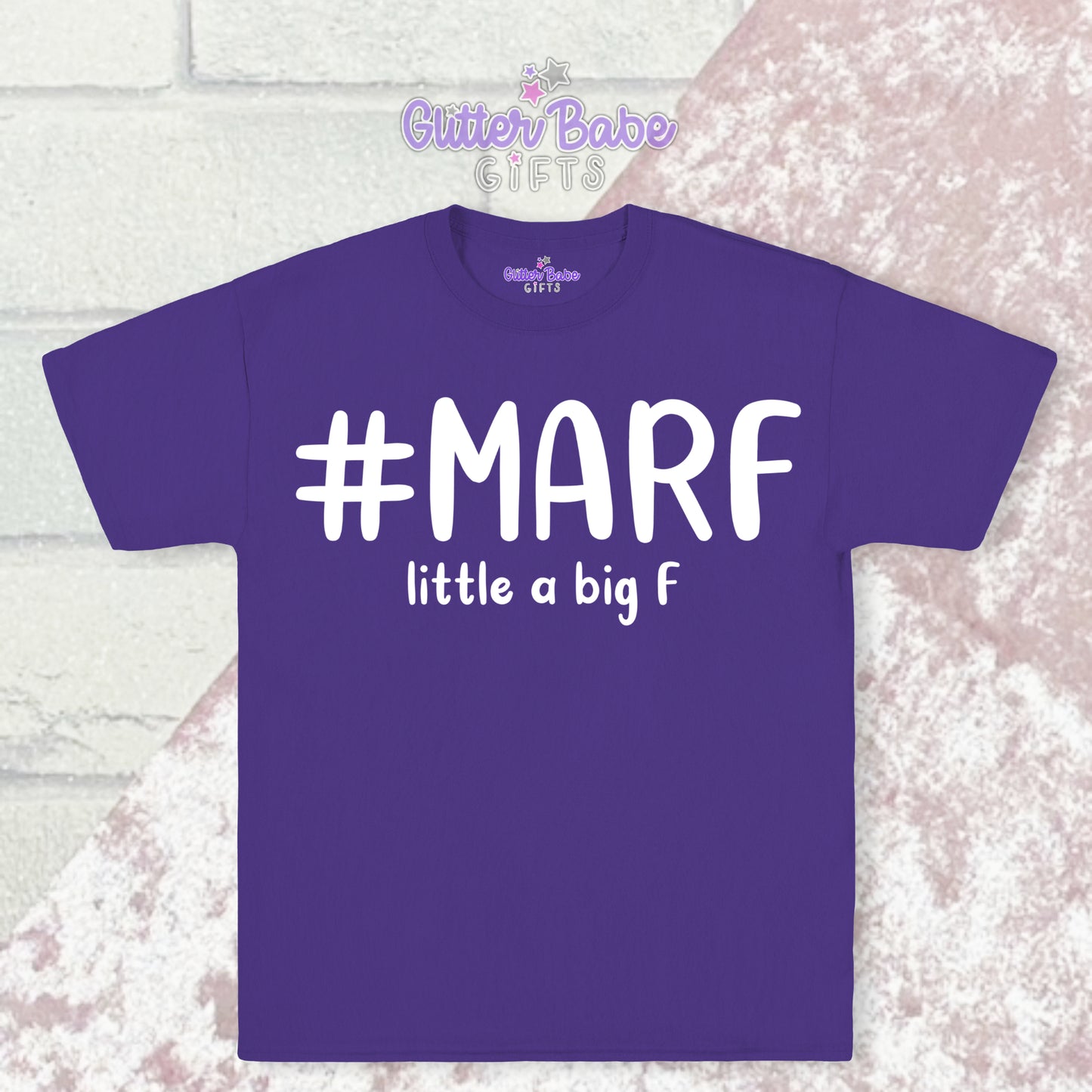 Purple T-shirt with white writing saying #marf little a big f with a pale pink and white backdrop