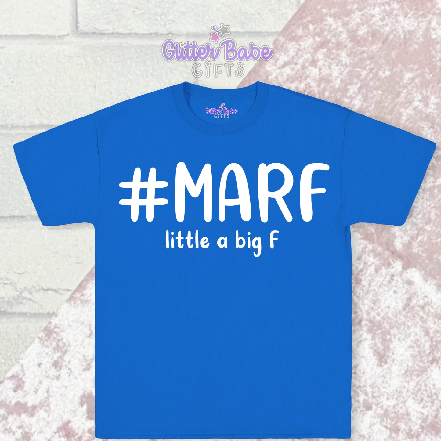 Blue T-shirt with white writing saying #marf little a big f with a pale pink and white backdrop