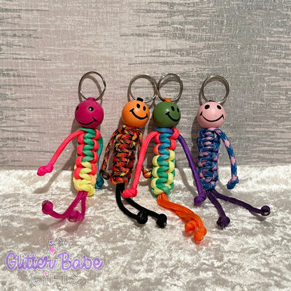 4 Keyrings made of colourful paracord with wooden smiley faced bead as head and dangly legs