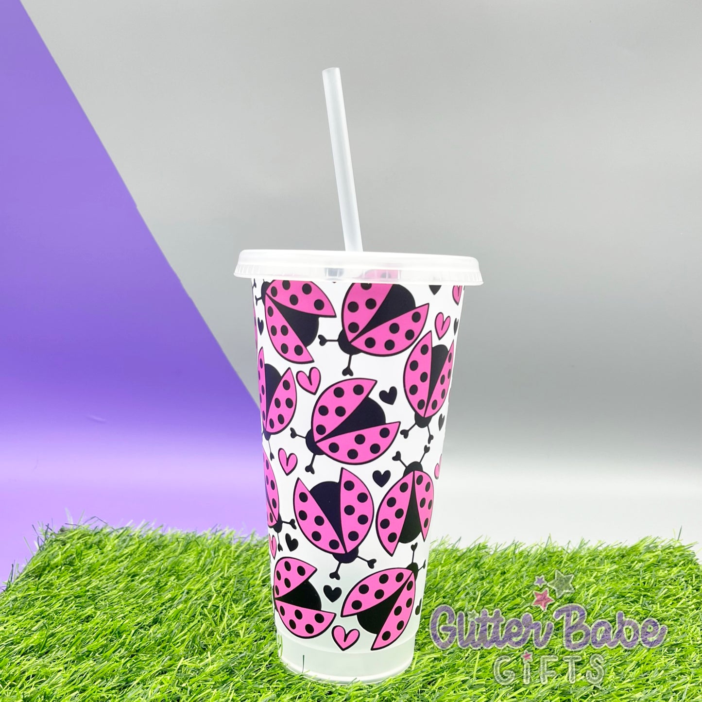 A frosted clear 24oz cold cup with a pink and black ladybug design, featuring a straw hole at the top.