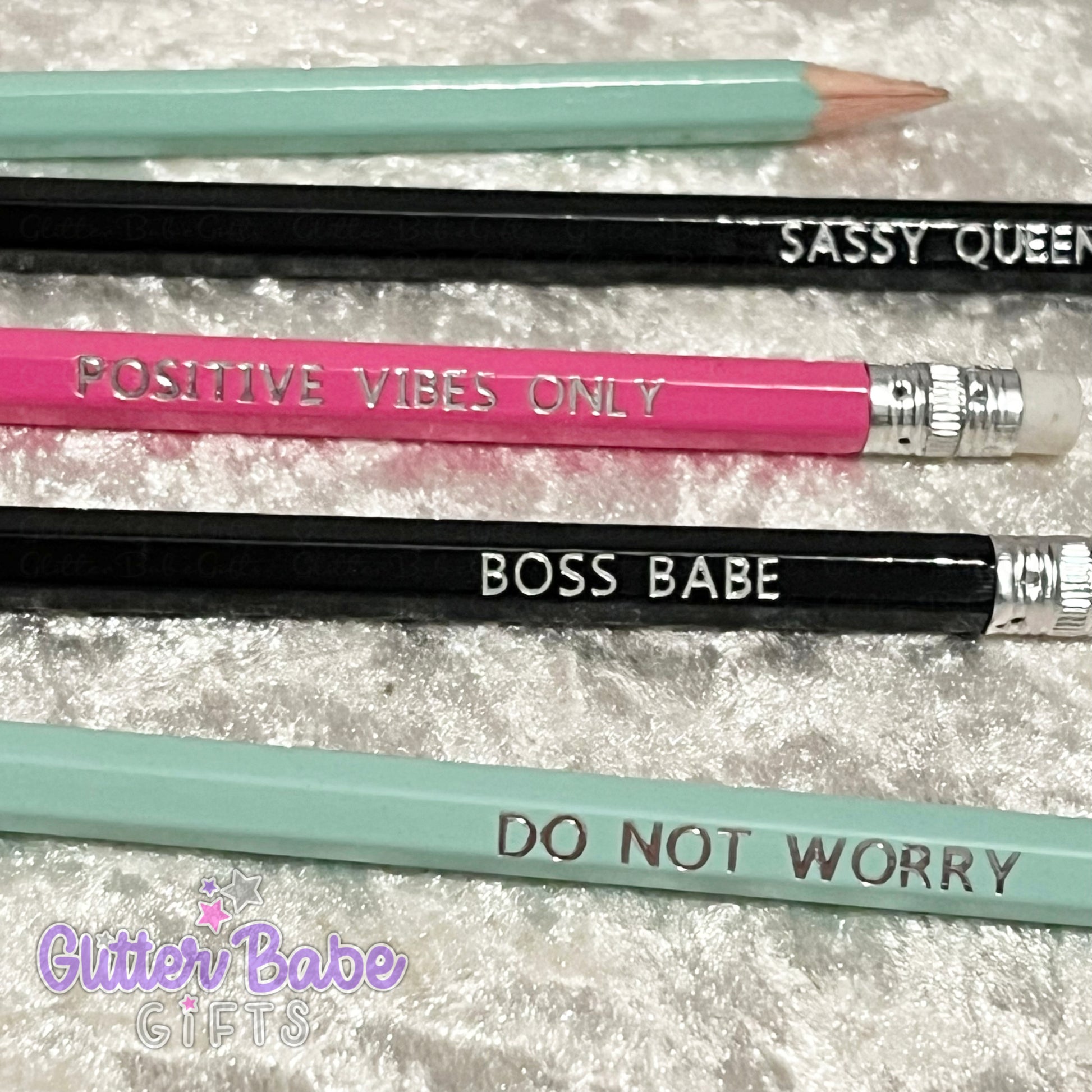A collection ofwriting pencils with various quotes foiled onto them, displayed on a textured background. Quotes include 'POSITIVE VIBES ONLY', 'SASSY QUEEN', 'BOSS BABE', and 'DO NOT WORRY'.