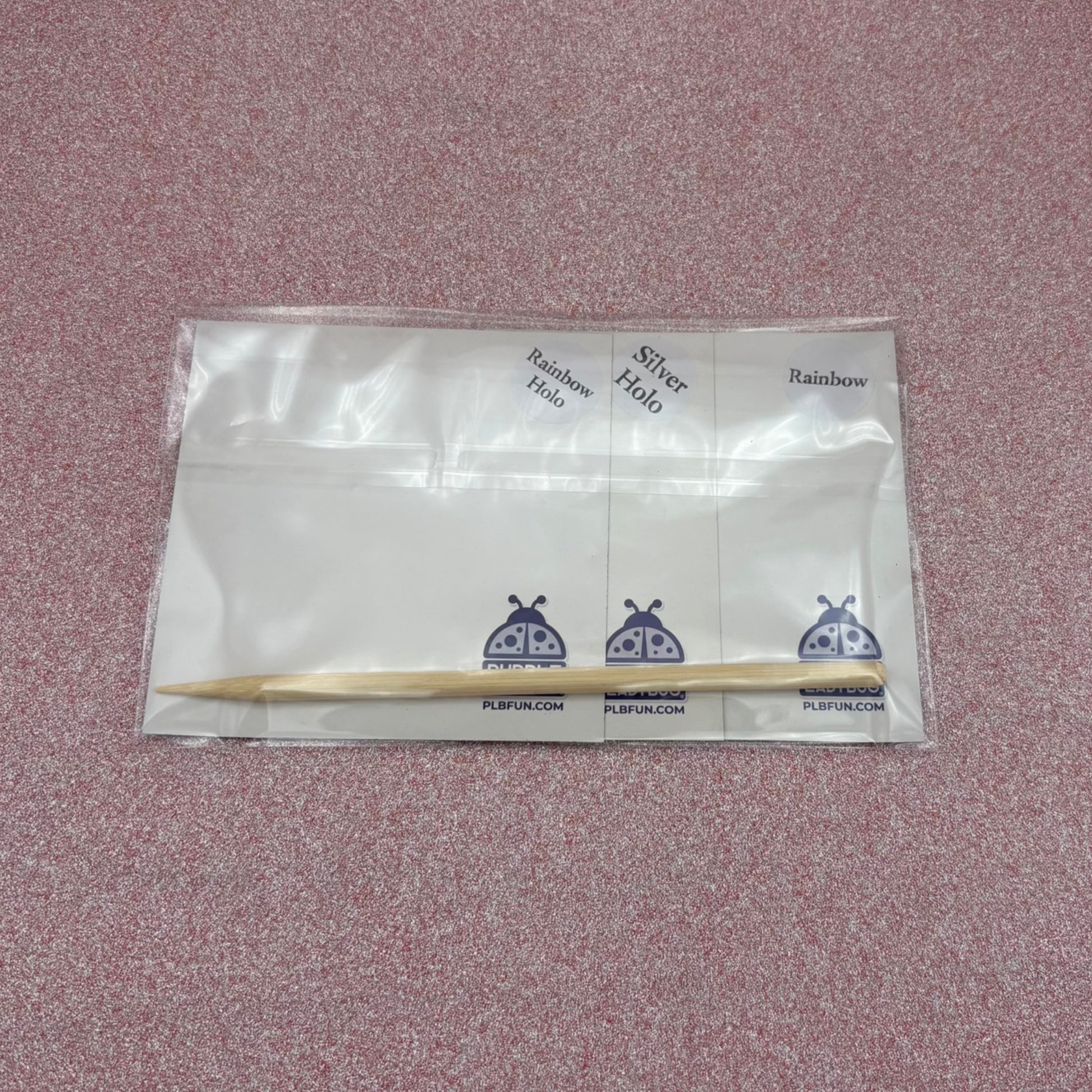 Back View of Packaged scratch art showing the wooden stylus and variations of scratch panels  on a textured pink background