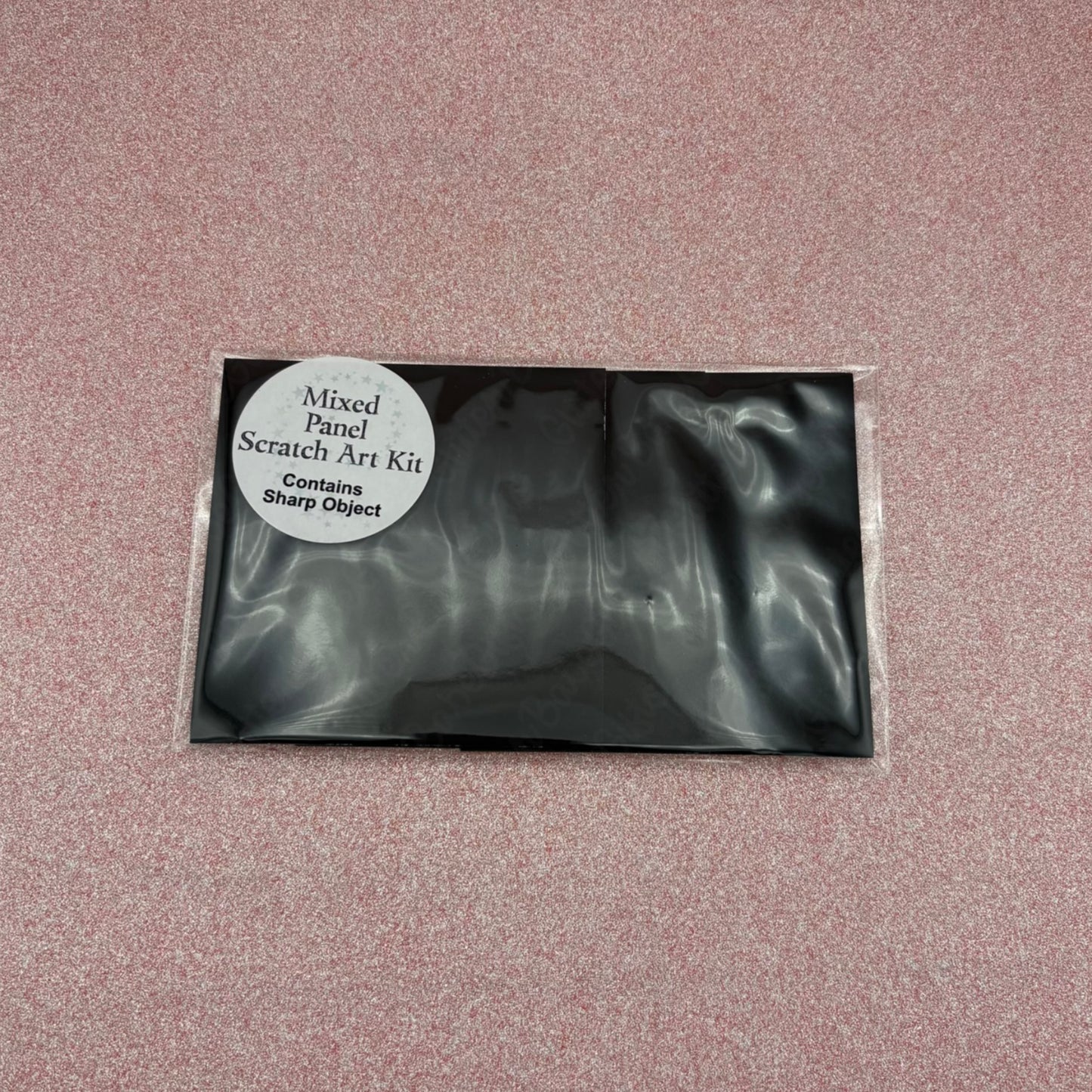 Black scratch art kit packaging on a pink textured background