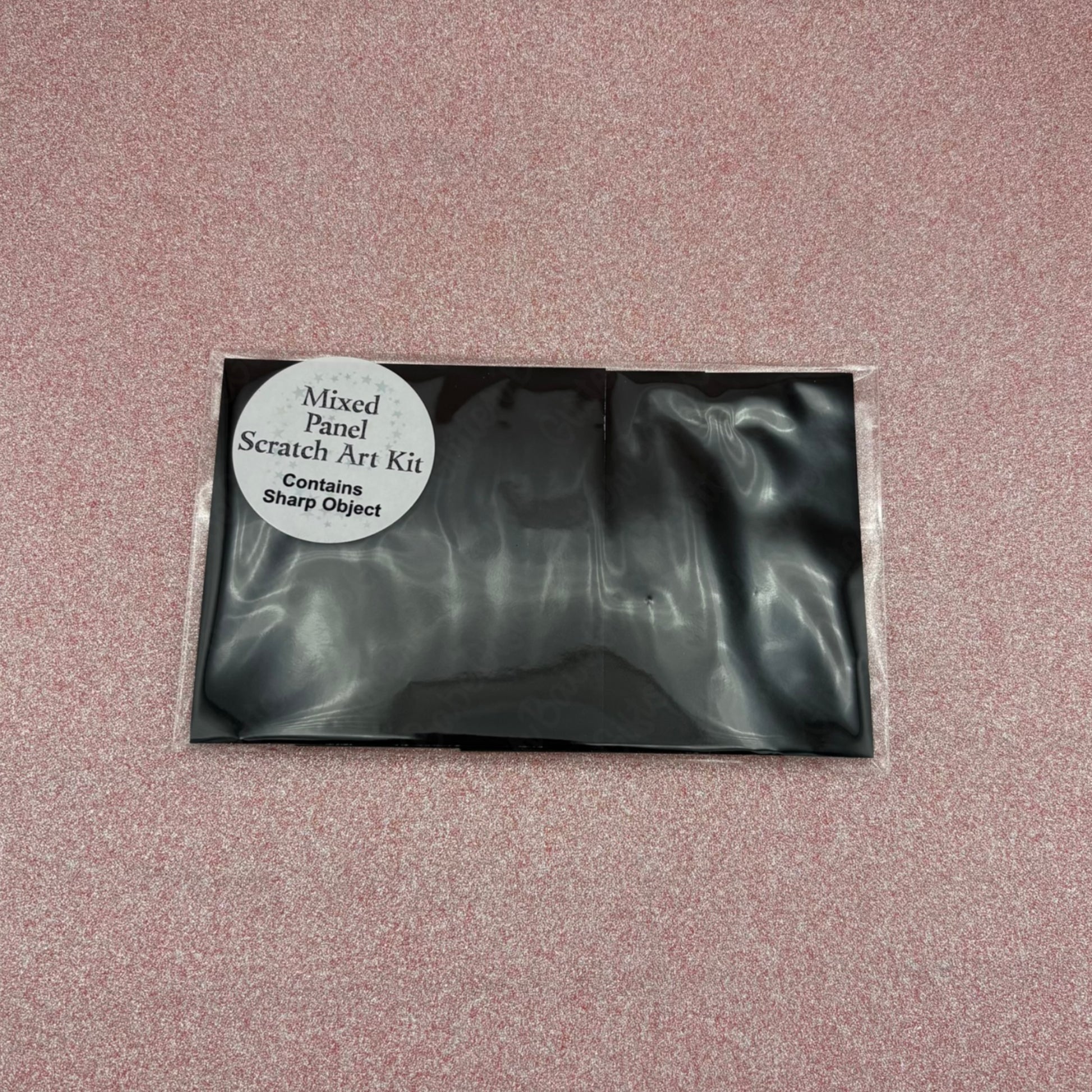Black scratch art kit packaging on a pink textured background