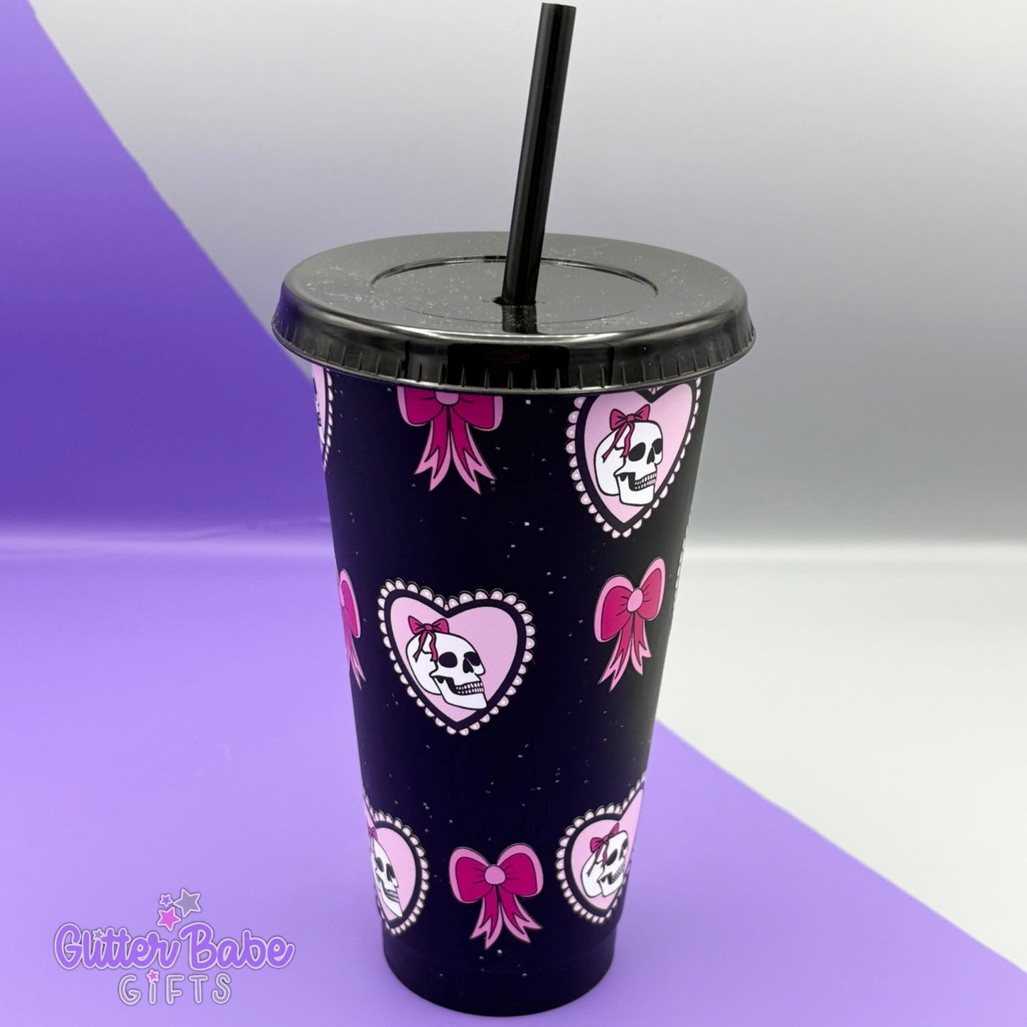 Black glittery tumbler with pink bow and skull designs on a purple and white background