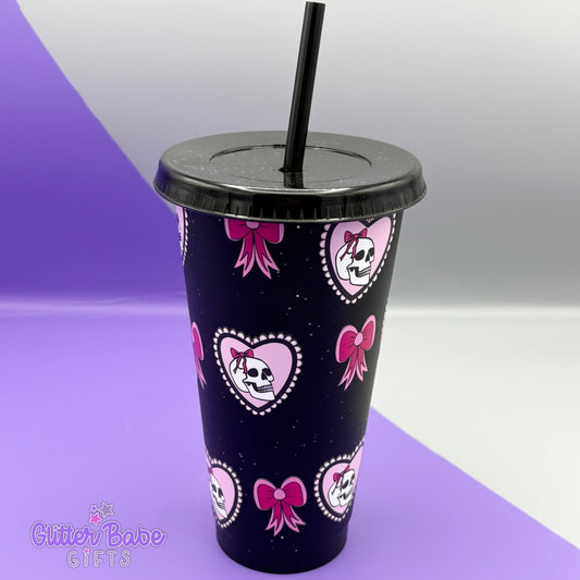 Black glittery tumbler with pink bow and skull designs on a purple and white background