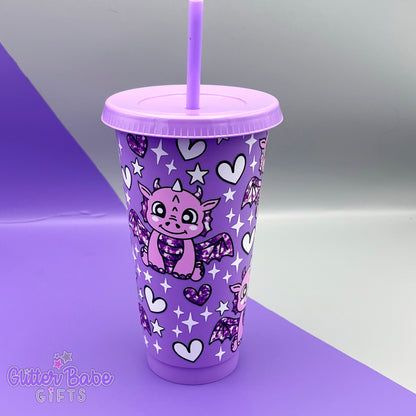 A lavender purple tumbler with purple dragon with scales, white hearts and stars design on a purple and grey backdrop