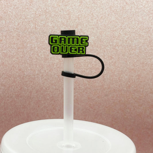 Clear straw with a black and green 'GAME OVER' topper on a pale pink background