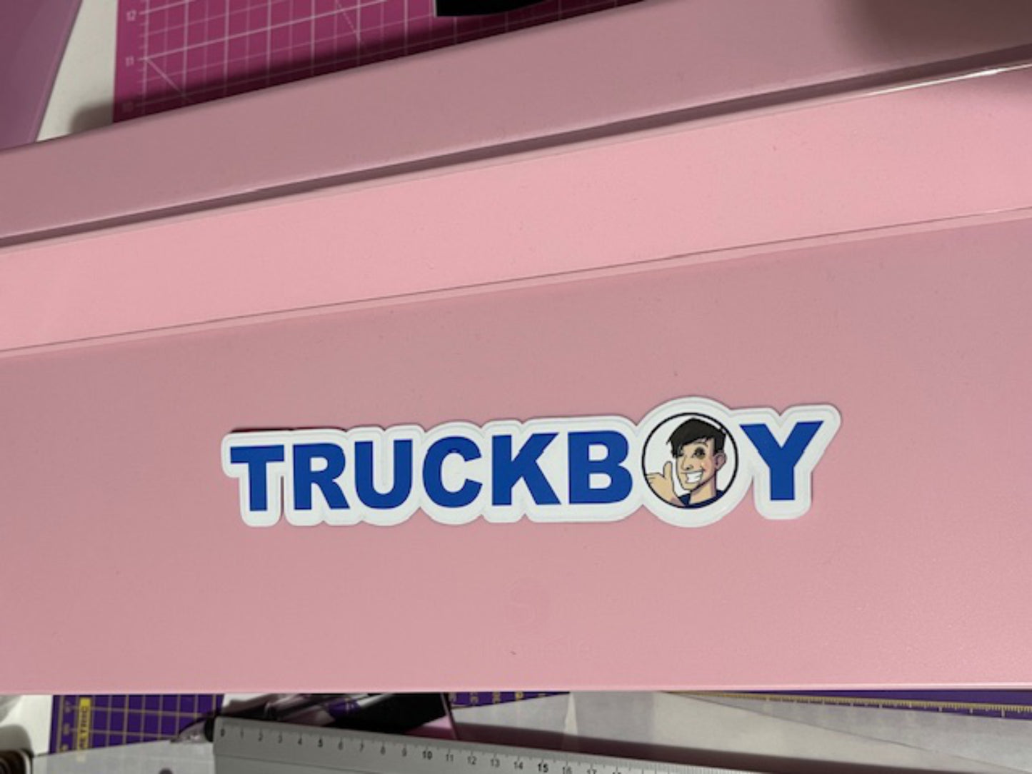 Pink machine with 'TRUCKBOY' logo sticker on it featuring a person's face.