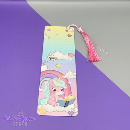 Colorful bookmark with a cartoon unicorn reading a book on a purple and gray background, featuring the brand 'Glitter Babe Gifts'.