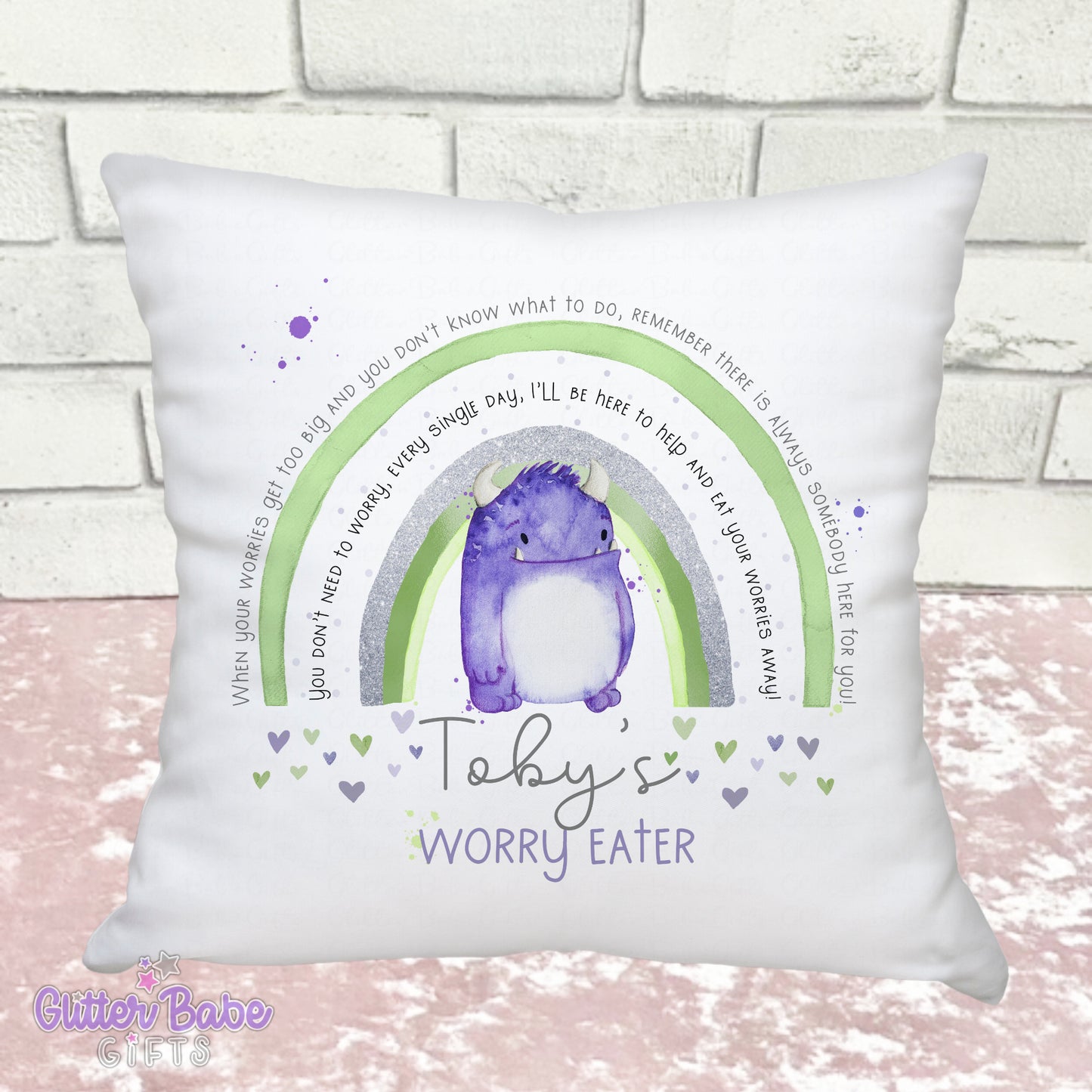 white cushion with a green rainbow and a purple monster image with writing on a pink and white background