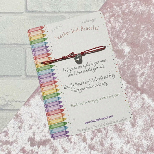 Red cord wish bracelet with silver coloured apple charm on a backing card that features colourful crayons and little poem