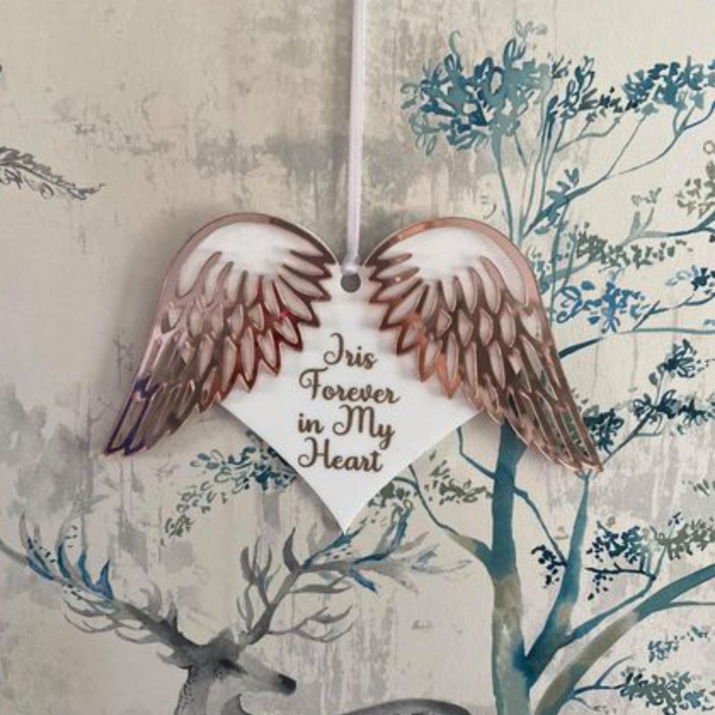 White hanging heart on white ribbon with mirrored rose gold wing details and writing in a matching gold 